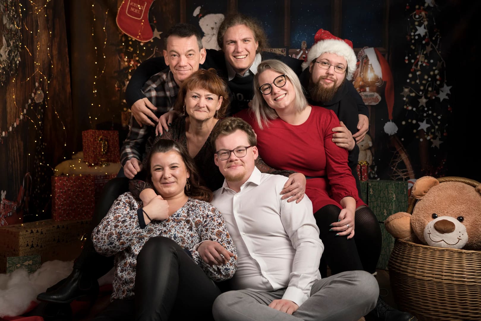 Une famille nombreuse de 7 personnes font des photos de groupe pendant un shooting dans un décor de Noël