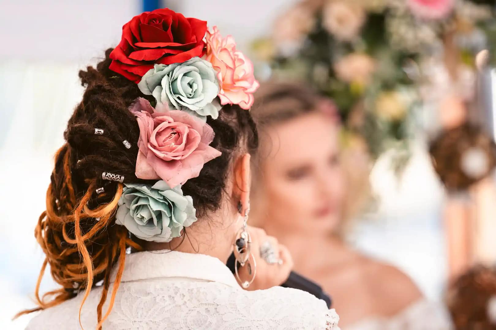 une invitée d'un mariage est prise de photo de dos, elle porte des fleurs colorées dans ses cheveux