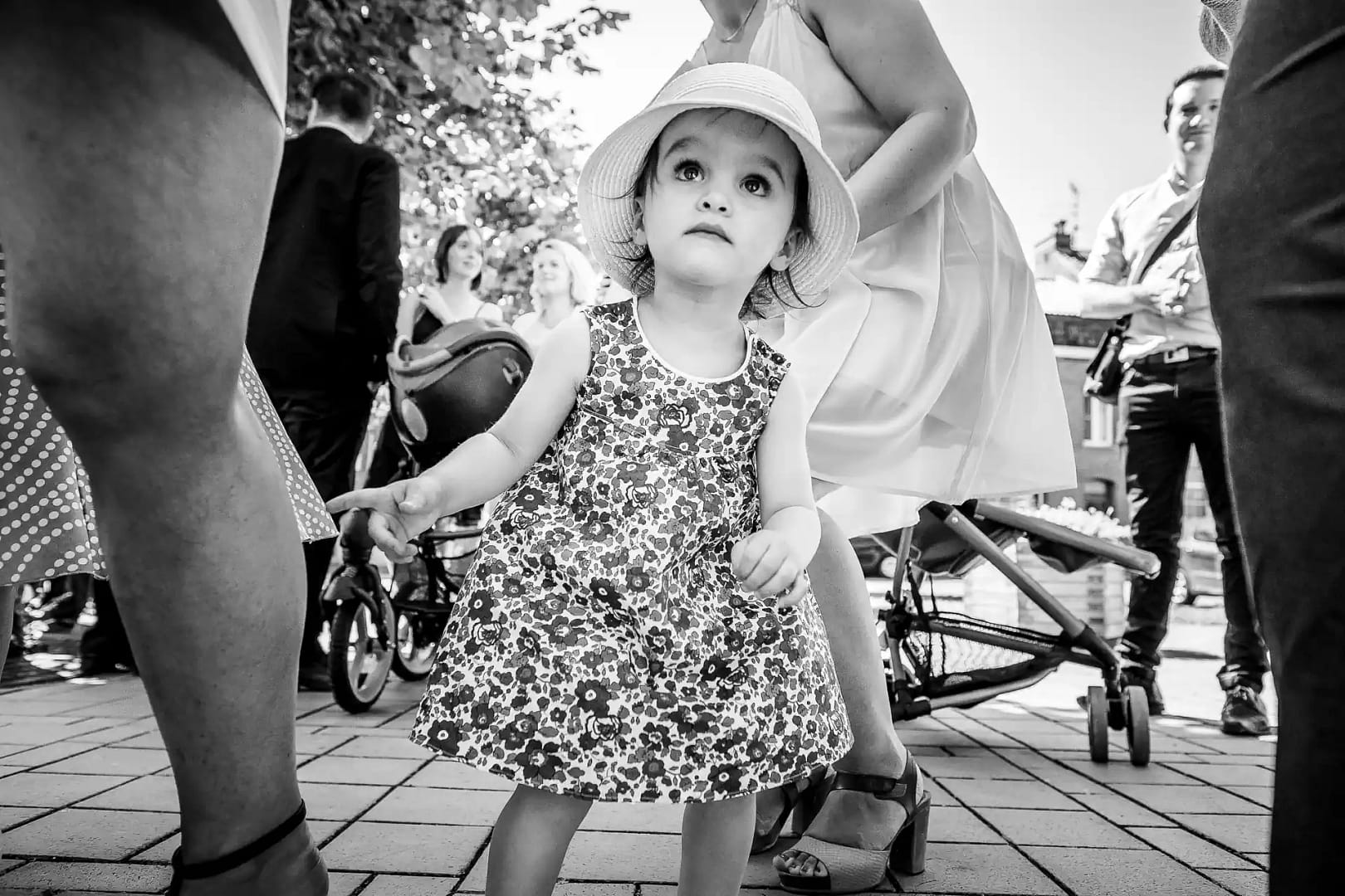 photo en noir et blanc d'une petite enfant en robe à fleur et qui porte un chapeau