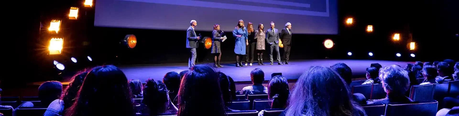 reportage entreprise pour le festival Séries Mania 2025 à Lille. Les jurys de la compétition sont sur scène et font face à un public assis sur des fauteuils. Derrière le jury se dresse un écran géant.