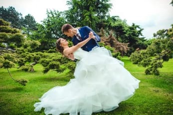 couple de mariées dans un parc. Le marié tient dans ses bras la mariée et la renverse en arrière