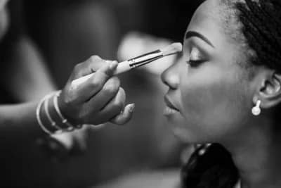 photo en noir et blanc d'une femme se faisant maquiller le visage